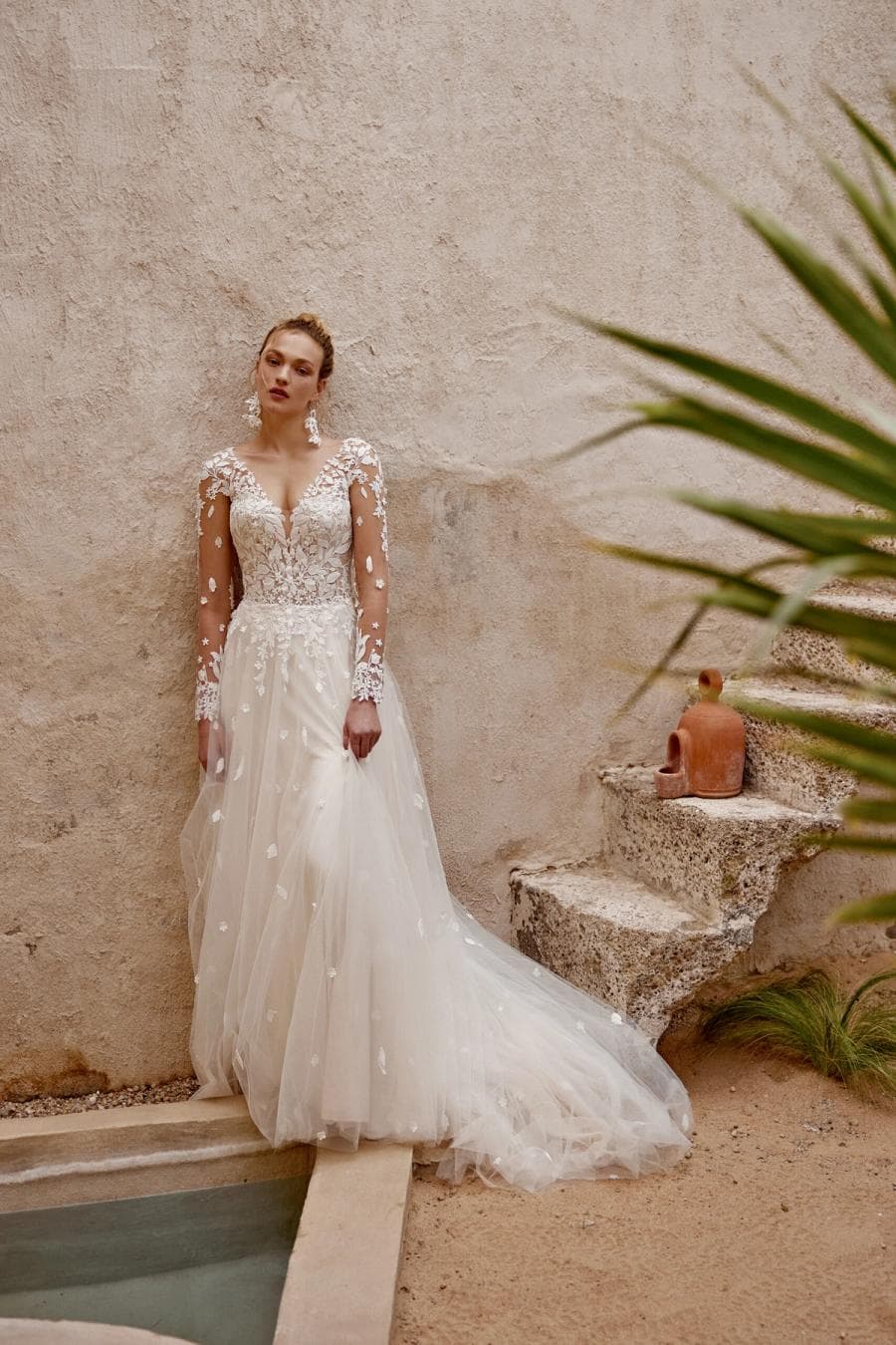 66368 by Lillian West, a floral lace bridal gown beside a stone pool