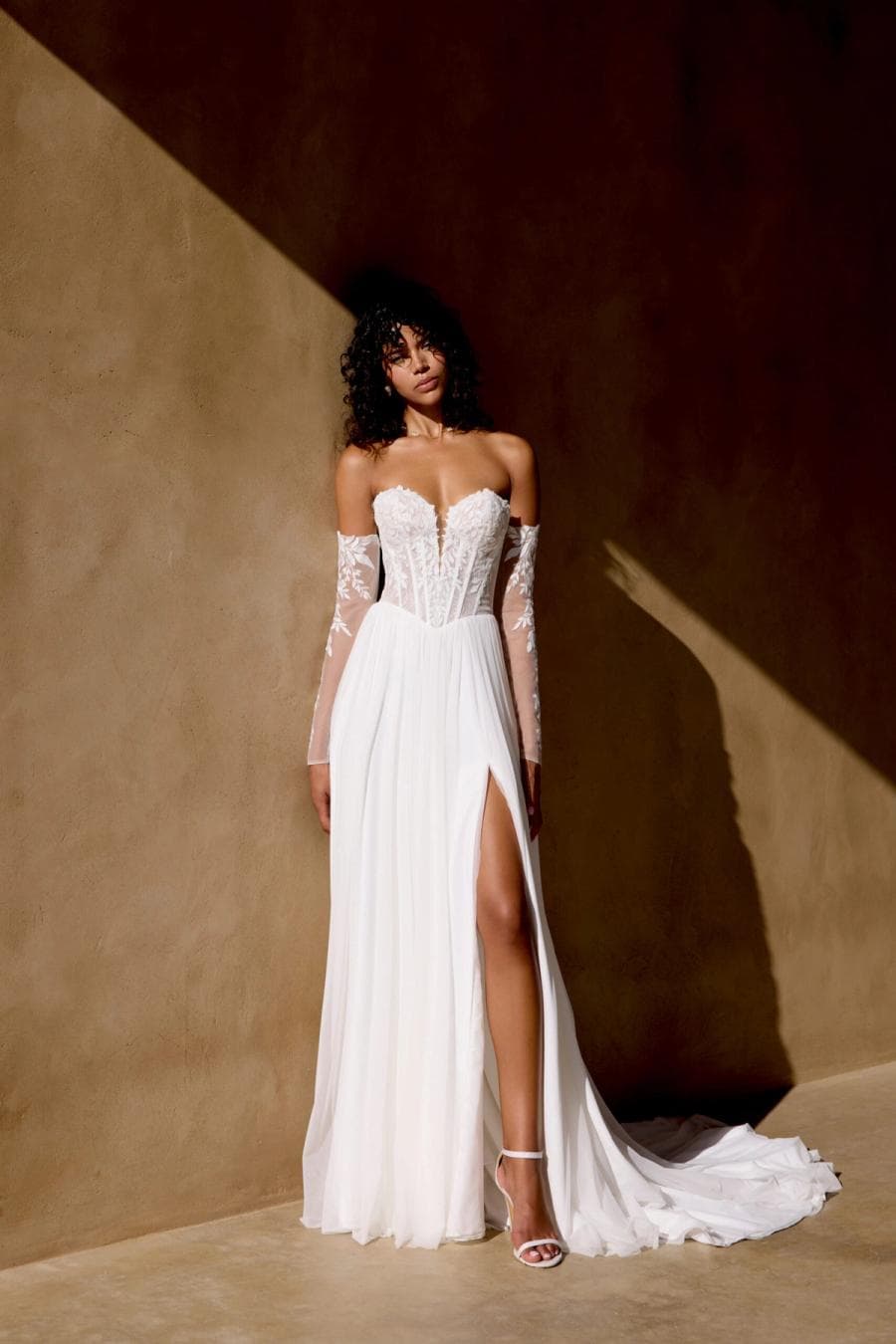 66452 by Lillian West, a bridal gown with floral sleeves in dramatic architectural light