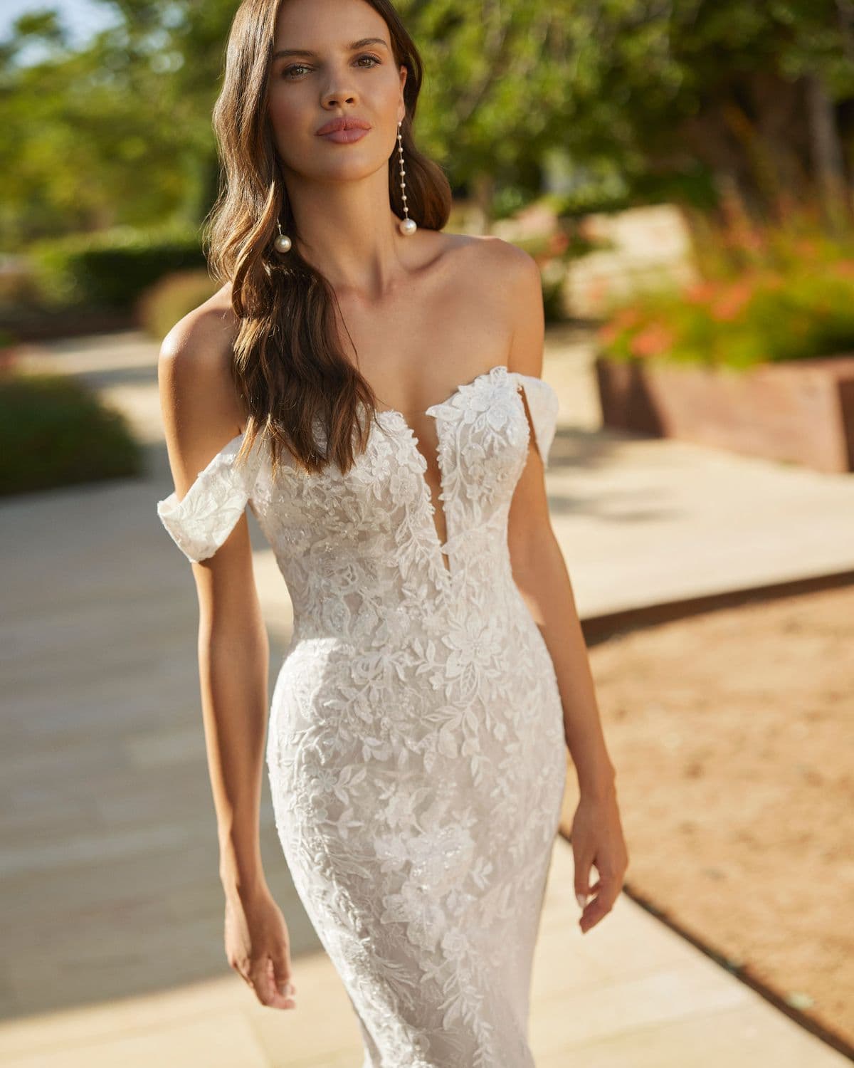 Sena by Adriana Alier, a bridal gown in a sunlit garden setting